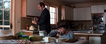 Movie still from “The NeverEnding Story” (1984), directed by Wolfgang Petersen – A man and a boy in a kitchen eating food; Medium shot, Over the shoulder angle