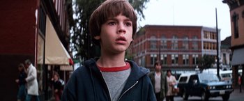 Movie still from “The NeverEnding Story” (1984), directed by Wolfgang Petersen – A young boy is standing in front of a group of people; Close Up shot, Low angle