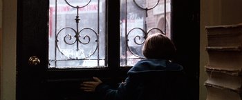 Movie still from “The NeverEnding Story” (1984), directed by Wolfgang Petersen – A person looking out of a window in a building; Medium shot, Over the shoulder angle