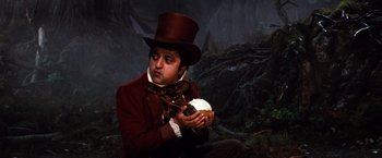 Movie still from “The NeverEnding Story” (1984), directed by Wolfgang Petersen – A man in a top hat holding a cupcake; Medium shot, High angle