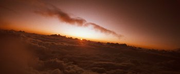 Movie still from “The NeverEnding Story” (1984), directed by Wolfgang Petersen – The sun is setting in the sky above the clouds; Extreme Wide shot, High angle