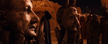 Movie still from “The NeverEnding Story” (1984), directed by Wolfgang Petersen – A man in a hooded cloak standing in front of statues; Close Up shot, Low angle