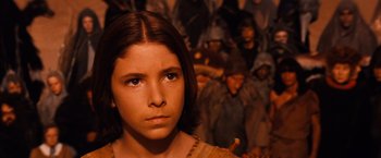 Movie still from “The NeverEnding Story” (1984), directed by Wolfgang Petersen – A young girl in front of a group of people; Close Up shot, High angle