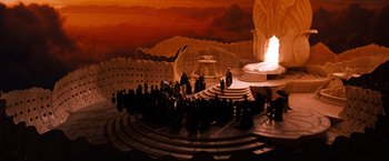 Movie still from “The NeverEnding Story” (1984), directed by Wolfgang Petersen – A group of people standing in front of a stage; Extreme Wide shot, High angle