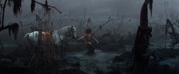 Movie still from “The NeverEnding Story” (1984), directed by Wolfgang Petersen – A white horse is walking through a swamp; Wide shot, High angle