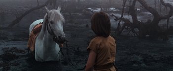 Movie still from “The NeverEnding Story” (1984), directed by Wolfgang Petersen – A young girl leading a white horse across a muddy field; Close Up shot, High angle