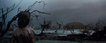 Movie still from “The NeverEnding Story” (1984), directed by Wolfgang Petersen – A woman standing in a field with dead trees; Wide shot, High angle