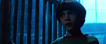 Movie still from “The NeverEnding Story” (1984), directed by Wolfgang Petersen – A young boy is standing in front of a wooden fence; Close Up shot, Low angle