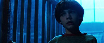 Movie still from “The NeverEnding Story” (1984), directed by Wolfgang Petersen – A young boy is standing in a dark room; Close Up shot, Low angle