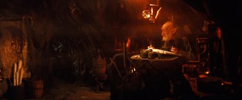 Movie still from “The NeverEnding Story” (1984), directed by Wolfgang Petersen – An old man sitting at a table in front of a fire; Wide shot, Over the shoulder angle