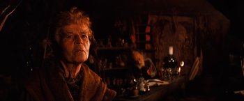 Movie still from “The NeverEnding Story” (1984), directed by Wolfgang Petersen – An older woman sitting in front of a table; Close Up shot, Over the shoulder angle