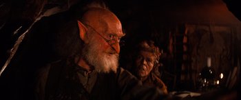 Movie still from “The NeverEnding Story” (1984), directed by Wolfgang Petersen – An old man and a woman are looking at the camera; Close Up shot, Over the shoulder angle