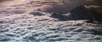 Movie still from “The NeverEnding Story” (1984), directed by Wolfgang Petersen – An airplane is flying above the clouds in the sky; Extreme Wide shot, High angle
