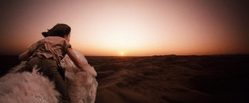 Movie still from “The NeverEnding Story” (1984), directed by Wolfgang Petersen – The sun is setting in the desert with sand dunes in the background; Wide shot, Low angle