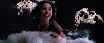Movie still from “The NeverEnding Story” (1984), directed by Wolfgang Petersen – A woman smiling while sitting on top of a pile of snow; Medium shot, Overhead angle