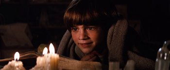 Movie still from “The NeverEnding Story” (1984), directed by Wolfgang Petersen – A young boy reading a book by a candle light; Close Up shot, High angle