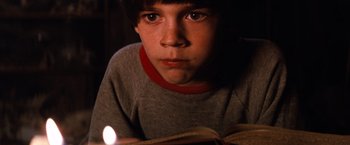 Movie still from “The NeverEnding Story” (1984), directed by Wolfgang Petersen – A young boy is reading a book in the dark; Close Up shot, High angle