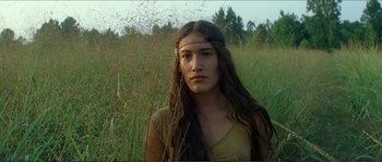 Movie still from “The New World” (2005), directed by Terrence Malick – A woman with long brown hair wearing a headband in a field of tall grass; Close Up shot, Low angle