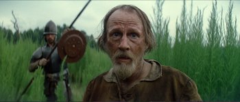 Movie still from “The New World” (2005), directed by Terrence Malick – An old man with a beard is standing in the grass; Close Up shot, Low angle