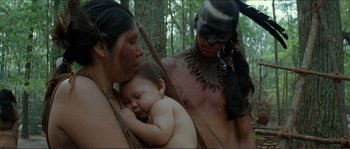 Movie still from “The New World” (2005), directed by Terrence Malick – A man and a woman holding a baby in front of a tree; Medium shot, Over the shoulder angle