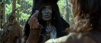 Movie still from “The New World” (2005), directed by Terrence Malick – A man with a face paint on his face and a fur coat on; Close Up shot, Over the shoulder angle