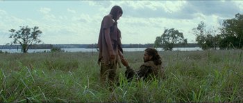 A man kneeling down next to a woman in a field