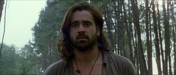 Movie still from “The New World” (2005), directed by Terrence Malick – A man with long hair and a beard is standing in the woods; Close Up shot, Low angle