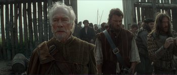 Movie still from “The New World” (2005), directed by Terrence Malick – Two men in medieval garb walking in a crowd; Medium shot, Low angle