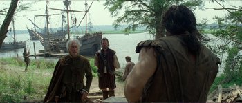 Movie still from “The New World” (2005), directed by Terrence Malick – A group of men standing next to a body of water; Wide shot, Over the shoulder angle