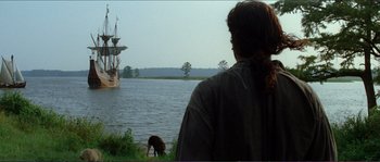 Movie still from “The New World” (2005), directed by Terrence Malick – A man looking out at a boat in a body of water; Extreme Wide shot, Over the shoulder angle