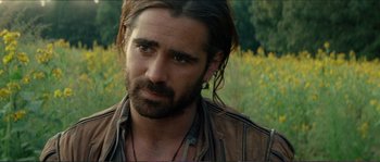 Movie still from “The New World” (2005), directed by Terrence Malick – A man with long hair and a beard is standing in a field; Close Up shot, Over the shoulder angle