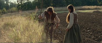 Movie still from “The New World” (2005), directed by Terrence Malick – A man and a woman are in a field with weeds; Wide shot, High angle