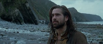 Movie still from “The New World” (2005), directed by Terrence Malick – A man with long hair standing on a rocky beach; Close Up shot, Low angle