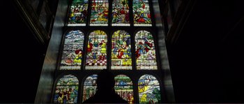 Movie still from “The New World” (2005), directed by Terrence Malick – A stained - glass window with a man standing in front of it; Extreme Wide shot, Low angle