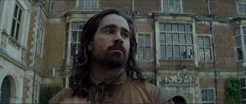 Movie still from “The New World” (2005), directed by Terrence Malick – A man with long hair standing in front of a building; Close Up shot, Low angle