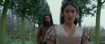 Movie still from “The New World” (2005), directed by Terrence Malick – A man and a woman standing next to each other in front of trees; Close Up shot, Low angle