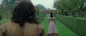 Movie still from “The New World” (2005), directed by Terrence Malick – Two people in medieval costumes walking through a garden; Wide shot, Over the shoulder angle