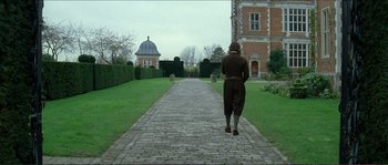 Movie still from “The New World” (2005), directed by Terrence Malick – A man walking down a brick path in front of a building; Wide shot, High angle