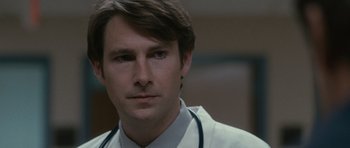 Movie still from “The Next Three Days” (2010), directed by Paul Haggis – A person wearing a lab coat and stethoscope; Close Up shot, Over the shoulder angle