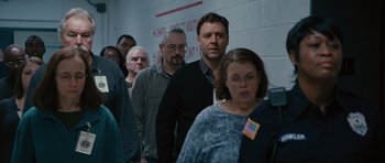 Movie still from “The Next Three Days” (2010), directed by Paul Haggis – A group of men and women standing in front of a brick wall; Medium shot, Over the shoulder angle