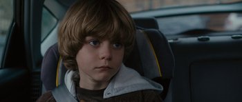 Movie still from “The Next Three Days” (2010), directed by Paul Haggis – A young boy sitting in the back seat of a car; Close Up shot, Over the shoulder angle