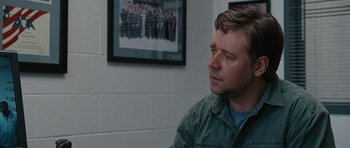 Movie still from “The Next Three Days” (2010), directed by Paul Haggis – A man sitting in front of a picture of a group of people; Close Up shot, Over the shoulder angle