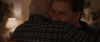 Movie still from “The Next Three Days” (2010), directed by Paul Haggis – A man hugging another man in a black and white plaid shirt; Close Up shot, Over the shoulder angle