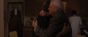 Movie still from “The Next Three Days” (2010), directed by Paul Haggis – An older man hugging a younger man in a kitchen; Medium shot, Over the shoulder angle