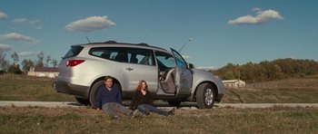 Movie still from “The Next Three Days” (2010), directed by Paul Haggis – A man and a woman sitting in front of a silver car; Wide shot, Low angle