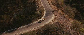 Movie still from “The Next Three Days” (2010), directed by Paul Haggis – An aerial view of a car driving down a curvy road; Extreme Wide shot, Overhead angle