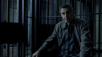 Movie still from “The Night Of” (2016), directed by James Marsh – A man sitting in front of a jail cell; Medium shot, High angle