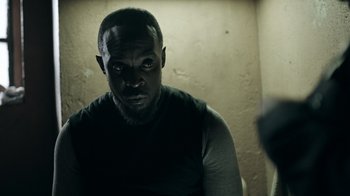 Movie still from “The Night Of” (2016), directed by James Marsh – A man in a black shirt is looking at the camera; Close Up shot, Over the shoulder angle