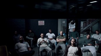 Movie still from “The Night Of” (2016), directed by James Marsh – A group of men sitting in chairs in a dark room; Wide shot, High angle