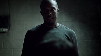 Movie still from “The Night Of” (2016), directed by James Marsh – A man in a black shirt is standing in a dark room; Close Up shot, Low angle